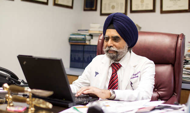 Physician working on computer at desk.